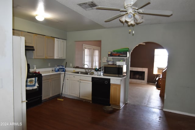 kitchen featuring ceiling fan, sink, dark hardwood / wood-style flooring, a tiled fireplace, and black appliances