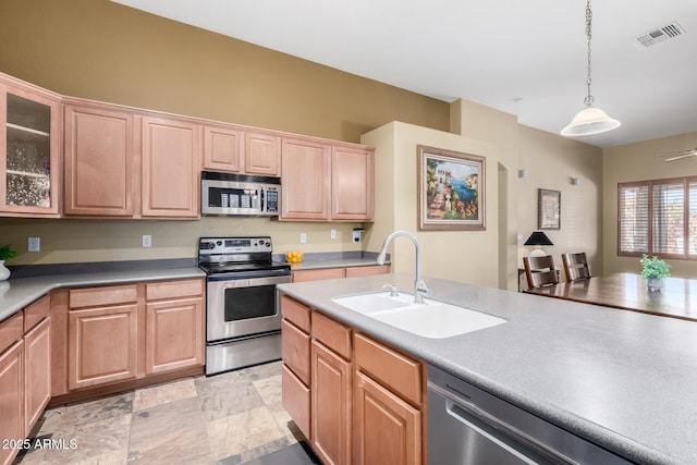 kitchen featuring visible vents, glass insert cabinets, decorative light fixtures, stainless steel appliances, and a sink