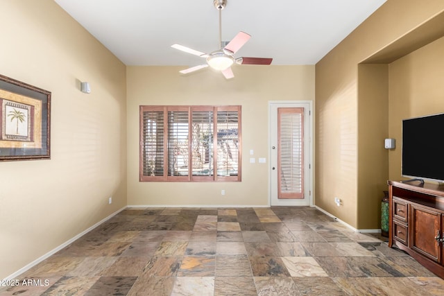 unfurnished living room featuring stone finish flooring, ceiling fan, and baseboards