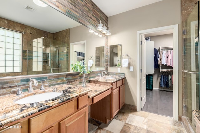 full bath featuring a shower stall, a sink, visible vents, and a walk in closet