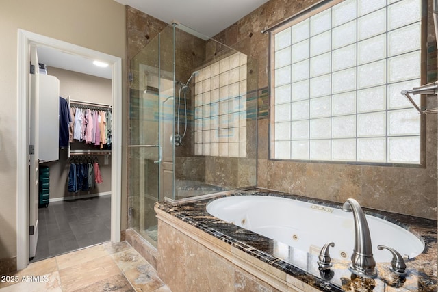 bathroom with a walk in closet, baseboards, a shower stall, and a whirlpool tub