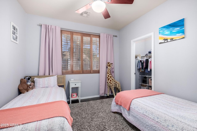 bedroom with a ceiling fan, a walk in closet, visible vents, and baseboards