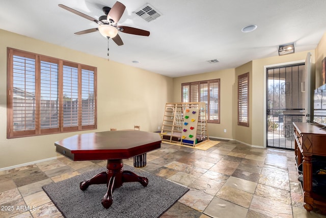 playroom with a ceiling fan, baseboards, visible vents, and stone tile floors