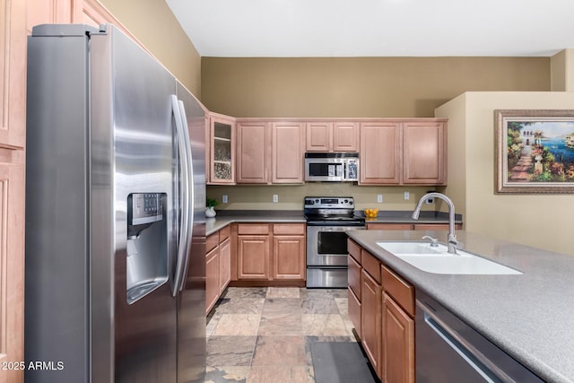 kitchen with stainless steel appliances, light countertops, glass insert cabinets, stone finish floor, and a sink