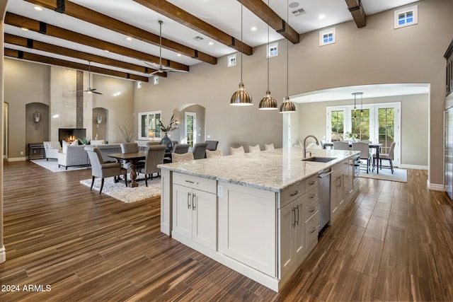 kitchen featuring light stone countertops, ceiling fan, sink, pendant lighting, and a fireplace