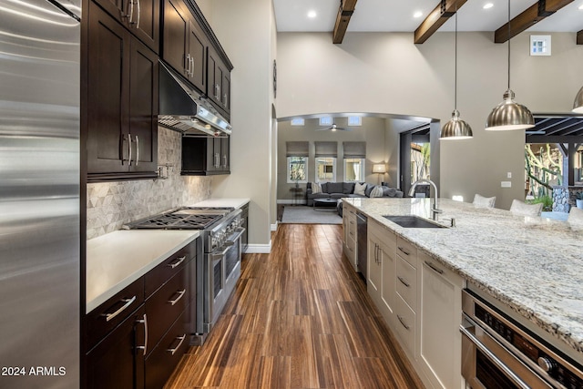 kitchen featuring decorative backsplash, ceiling fan, appliances with stainless steel finishes, beamed ceiling, and decorative light fixtures