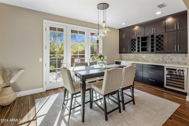 dining area with a healthy amount of sunlight, dark hardwood / wood-style flooring, beverage cooler, and indoor bar