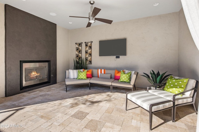 view of patio / terrace with an outdoor living space with a fireplace and ceiling fan