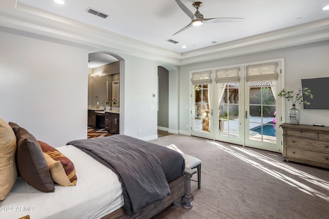 bedroom with ceiling fan, french doors, ensuite bathroom, a tray ceiling, and access to outside