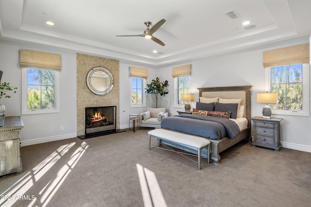 bedroom with multiple windows, a tray ceiling, and ceiling fan