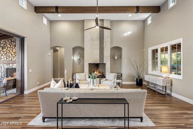 living room featuring hardwood / wood-style flooring, ceiling fan, a fireplace, and a high ceiling