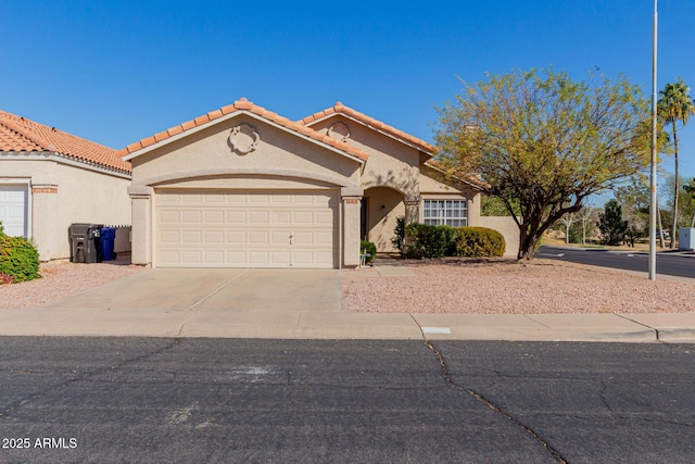 mediterranean / spanish-style home featuring concrete driveway, an attached garage, a tiled roof, and stucco siding