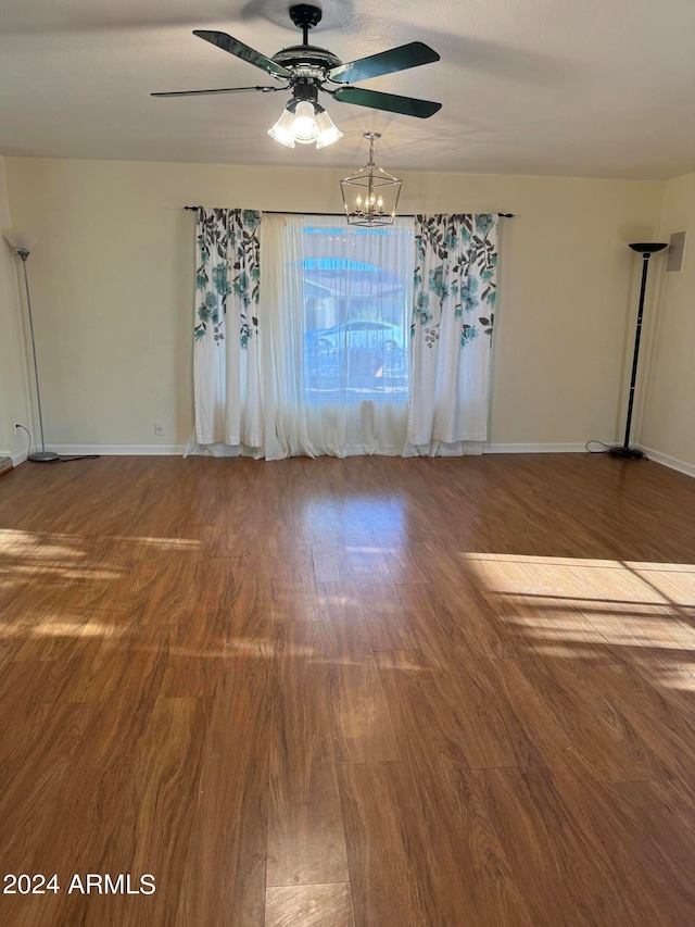 spare room with hardwood / wood-style flooring and ceiling fan with notable chandelier