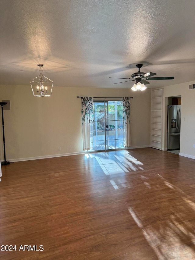 empty room with dark hardwood / wood-style floors, ceiling fan with notable chandelier, and a textured ceiling