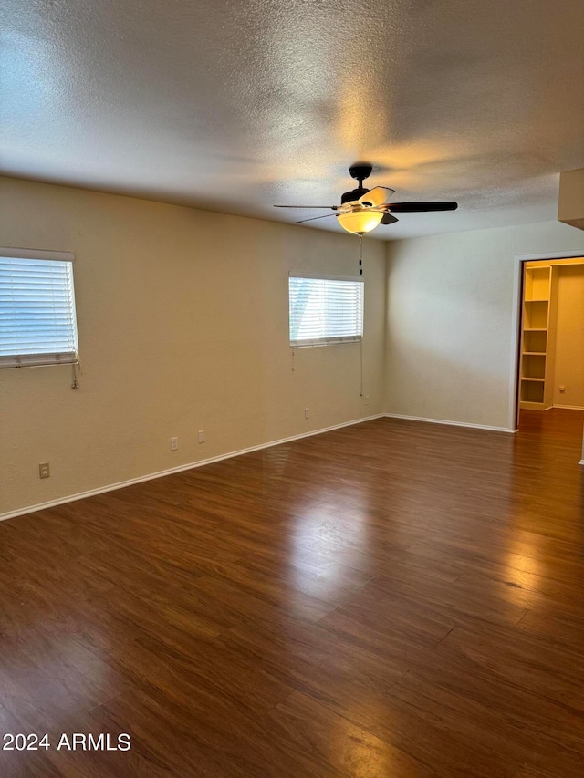 spare room with dark wood-type flooring, ceiling fan, and a textured ceiling