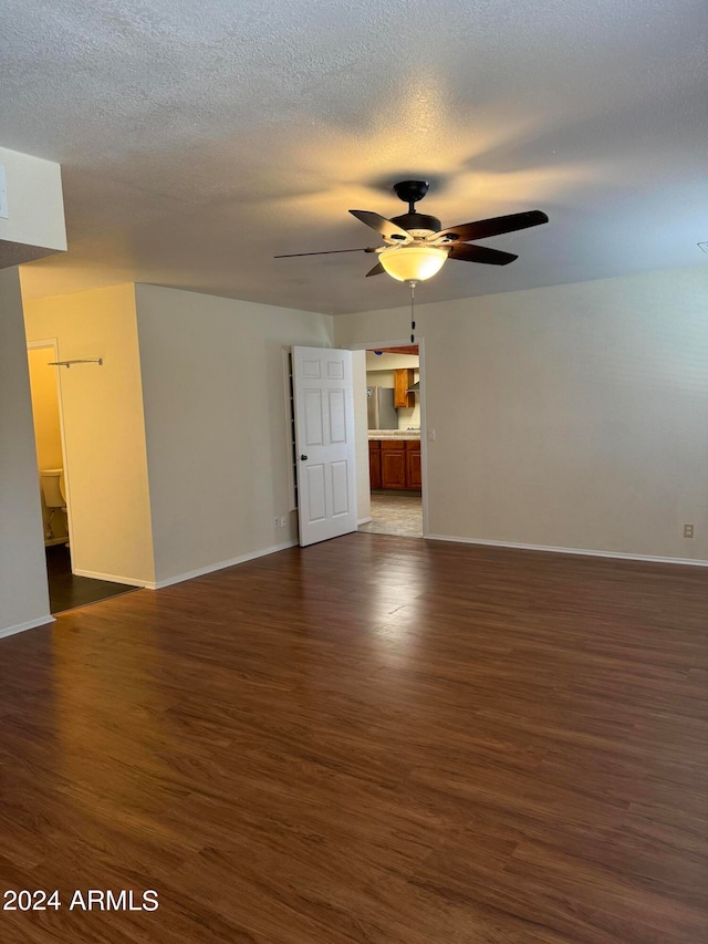 unfurnished room with ceiling fan, dark hardwood / wood-style flooring, and a textured ceiling