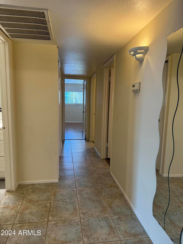 hall with tile floors and a textured ceiling