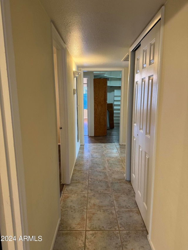 hallway featuring tile floors and a textured ceiling