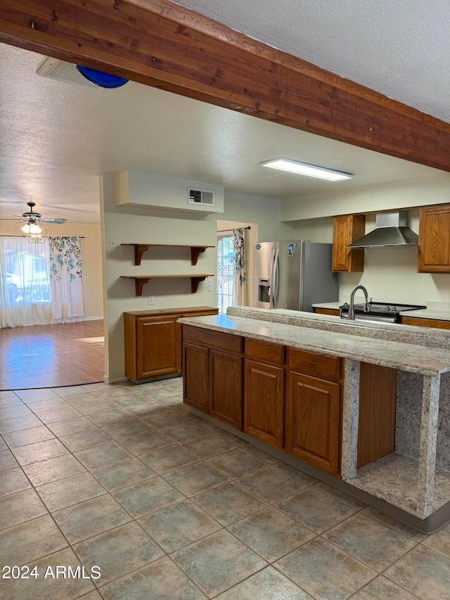 kitchen featuring appliances with stainless steel finishes, wall chimney range hood, a wealth of natural light, and a textured ceiling