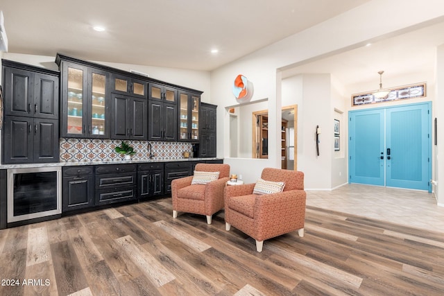 bar featuring backsplash, beverage cooler, wood-type flooring, hanging light fixtures, and lofted ceiling