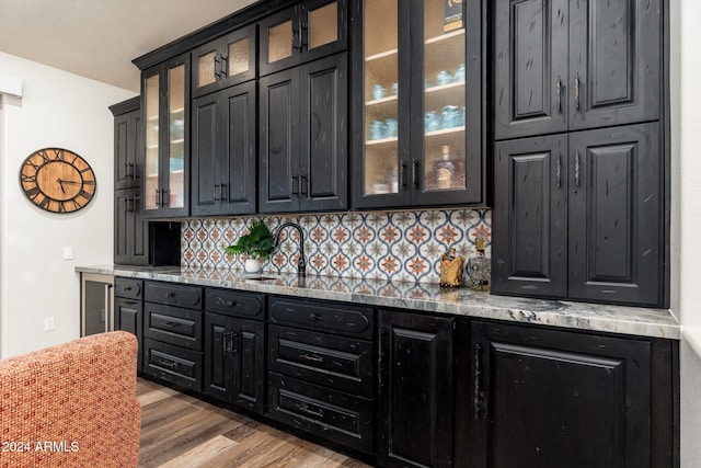 bar featuring decorative backsplash, dark hardwood / wood-style flooring, light stone countertops, and sink