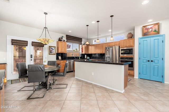 kitchen with appliances with stainless steel finishes, light tile patterned floors, decorative light fixtures, and a kitchen island