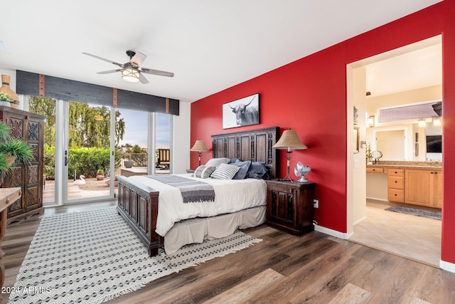 bedroom with ensuite bathroom, expansive windows, access to outside, ceiling fan, and dark wood-type flooring