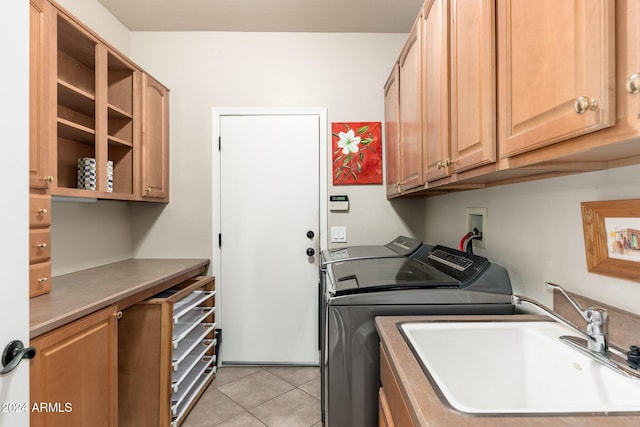 laundry room with washing machine and clothes dryer, sink, light tile patterned floors, and cabinets