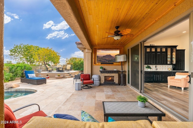 view of patio with ceiling fan and an outdoor stone fireplace