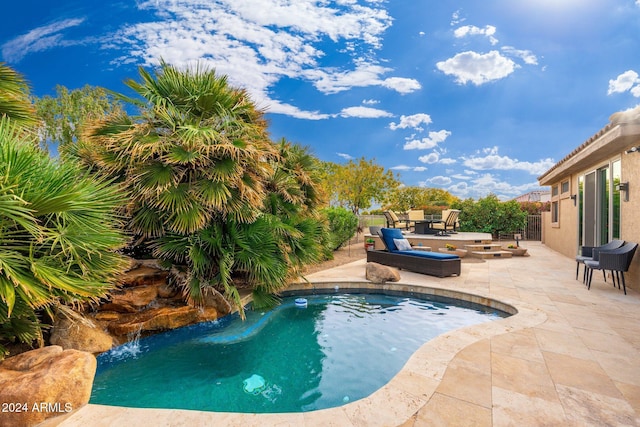 view of pool with pool water feature, outdoor lounge area, and a patio