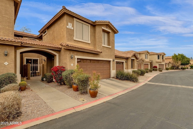 mediterranean / spanish-style home with an attached garage, a tile roof, concrete driveway, and stucco siding