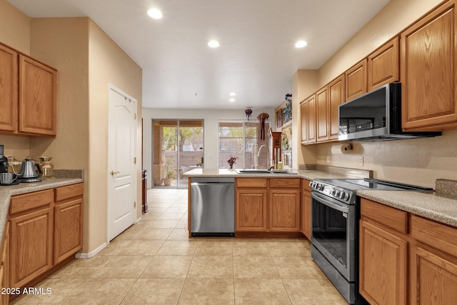 kitchen with appliances with stainless steel finishes, light countertops, a sink, and a peninsula