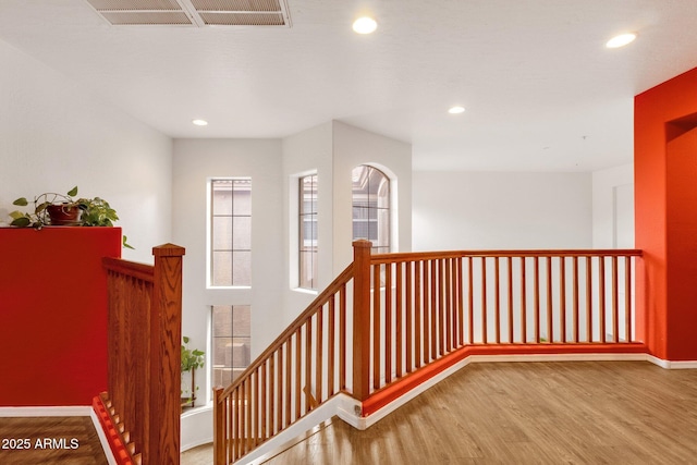 hallway with visible vents, wood finished floors, an upstairs landing, and recessed lighting