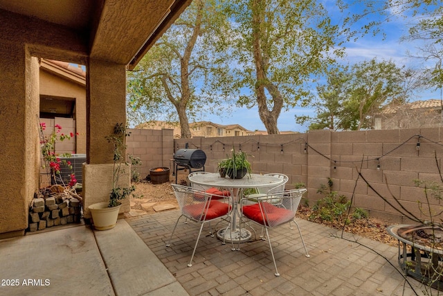 view of patio with outdoor dining area, a fenced backyard, and a grill