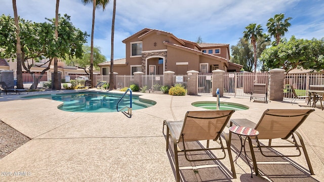 pool with a community hot tub, a patio area, and fence