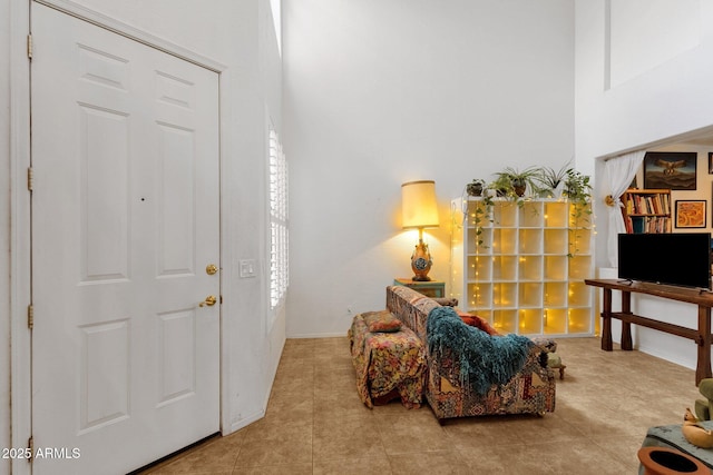 living area featuring tile patterned floors, a towering ceiling, and baseboards