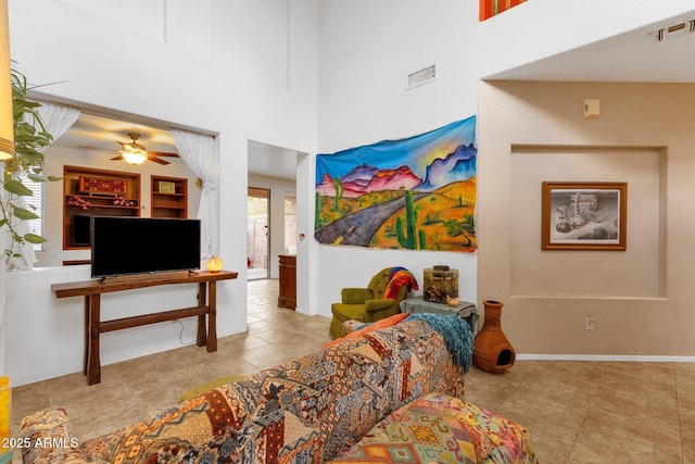 living room featuring baseboards, visible vents, a high ceiling, and tile patterned floors