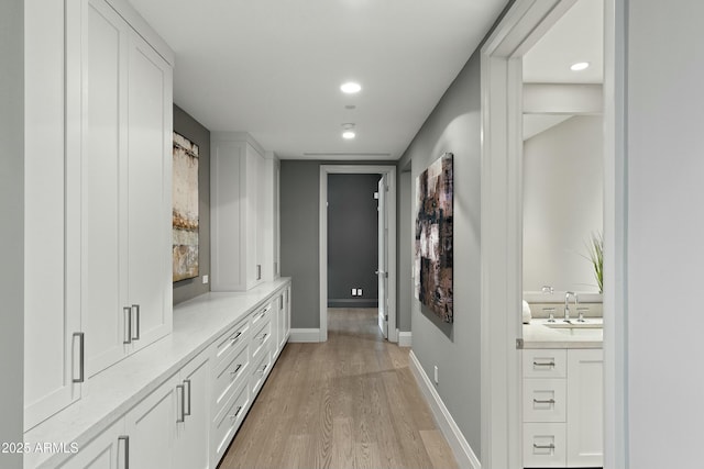 mudroom featuring light wood-type flooring, a sink, baseboards, and recessed lighting