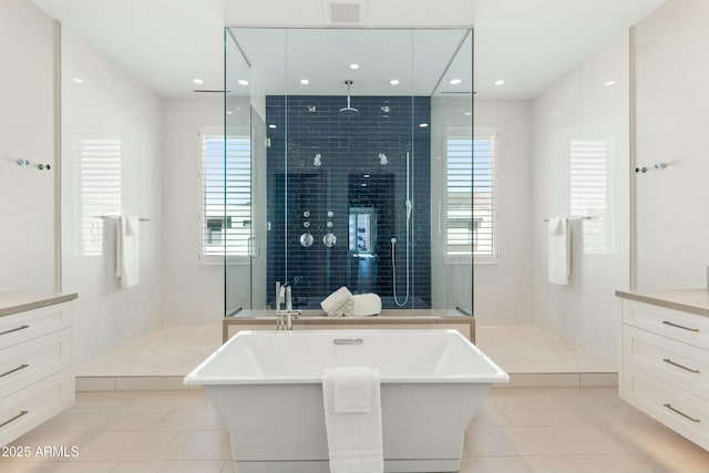 full bath with a freestanding bath, vanity, and tile patterned floors