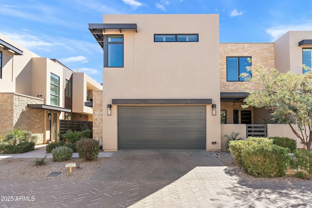 view of front facade featuring stone siding, decorative driveway, and stucco siding