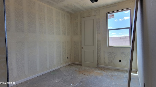 empty room with concrete floors and baseboards
