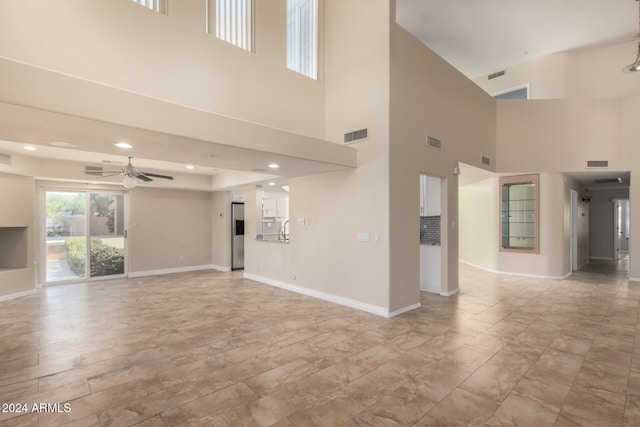 unfurnished living room with ceiling fan and a towering ceiling