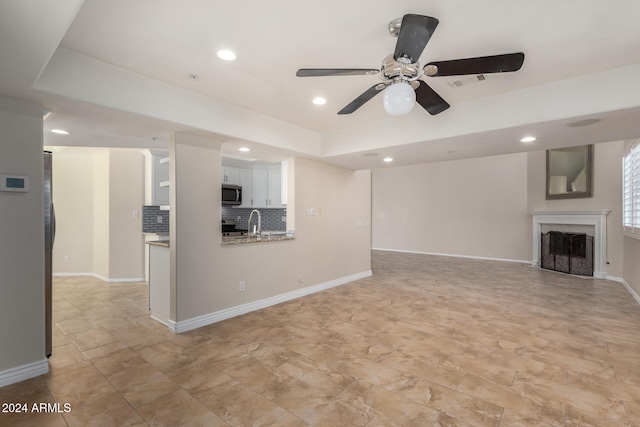 unfurnished living room featuring ceiling fan and sink