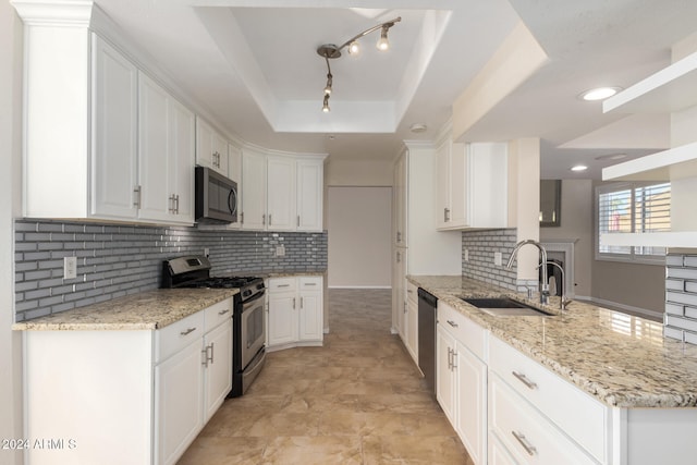 kitchen with a raised ceiling, sink, appliances with stainless steel finishes, light stone counters, and white cabinetry