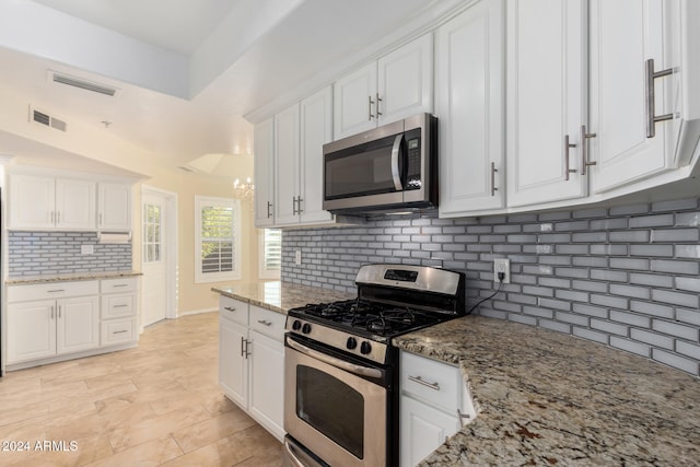 kitchen with white cabinets, light stone countertops, backsplash, and appliances with stainless steel finishes