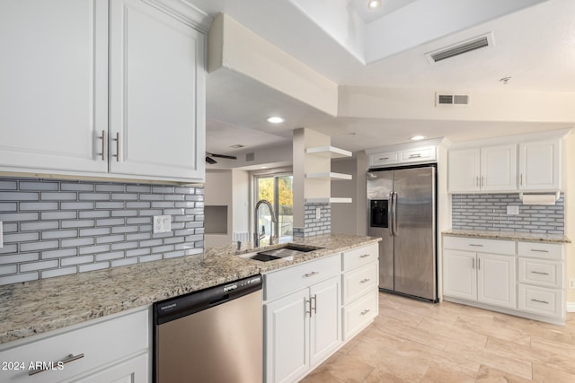 kitchen with white cabinetry, sink, light stone countertops, tasteful backsplash, and appliances with stainless steel finishes