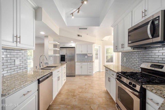 kitchen with light stone countertops, sink, tasteful backsplash, white cabinets, and appliances with stainless steel finishes