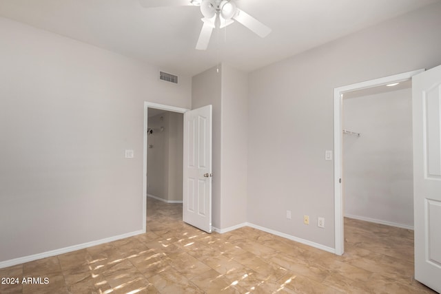 unfurnished bedroom with a closet, a spacious closet, and ceiling fan