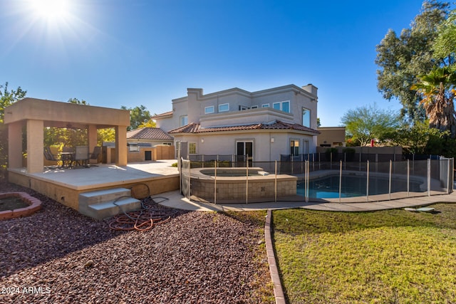 rear view of property with a gazebo, a patio area, a swimming pool with hot tub, and a lawn