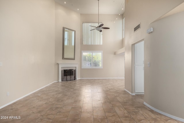 unfurnished living room featuring a towering ceiling and ceiling fan